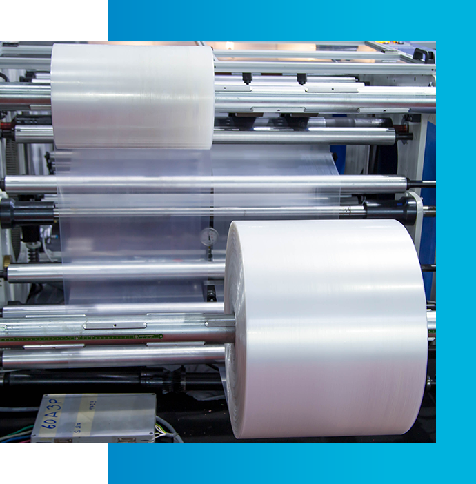 Plastic film rolls on industrial machinery conveyor system.
