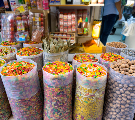 Colorful snacks and spices displayed in sacks at a bustling market stall.